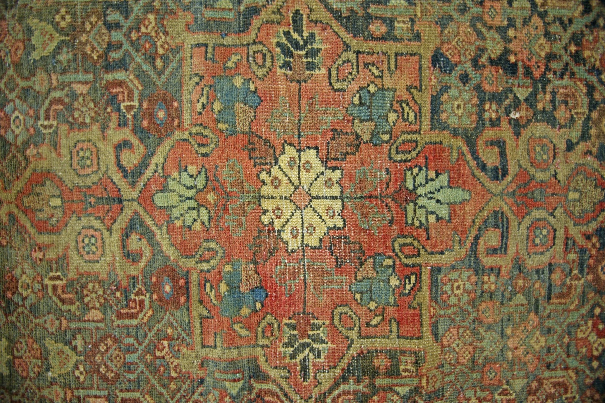 A vintage handmade Persian rug featuring a central floral medallion on a rust-colored field.