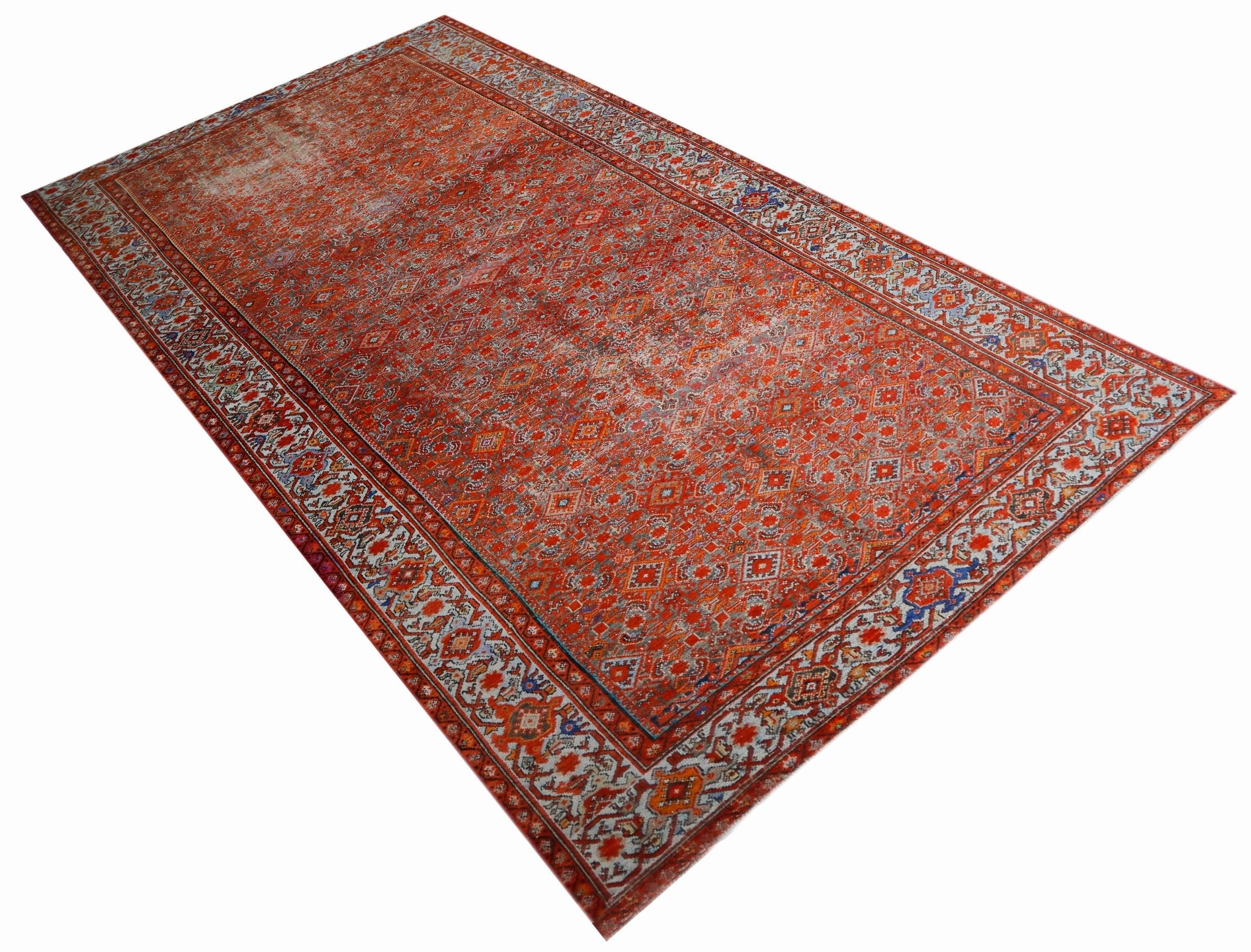 A rectangular vintage Persian rug featuring an intricate red geometric pattern and ornate borders.