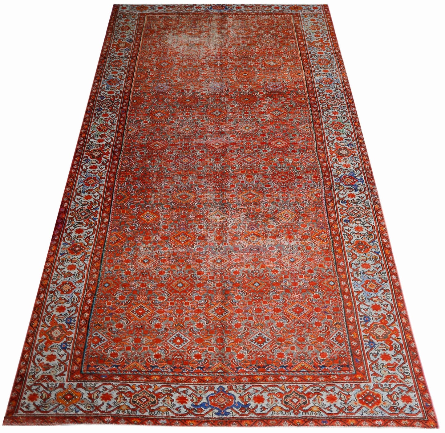 A rectangular vintage Persian rug featuring an intricate red geometric pattern and ornate borders.