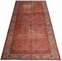 A rectangular vintage Persian rug featuring an intricate red geometric pattern and ornate borders.