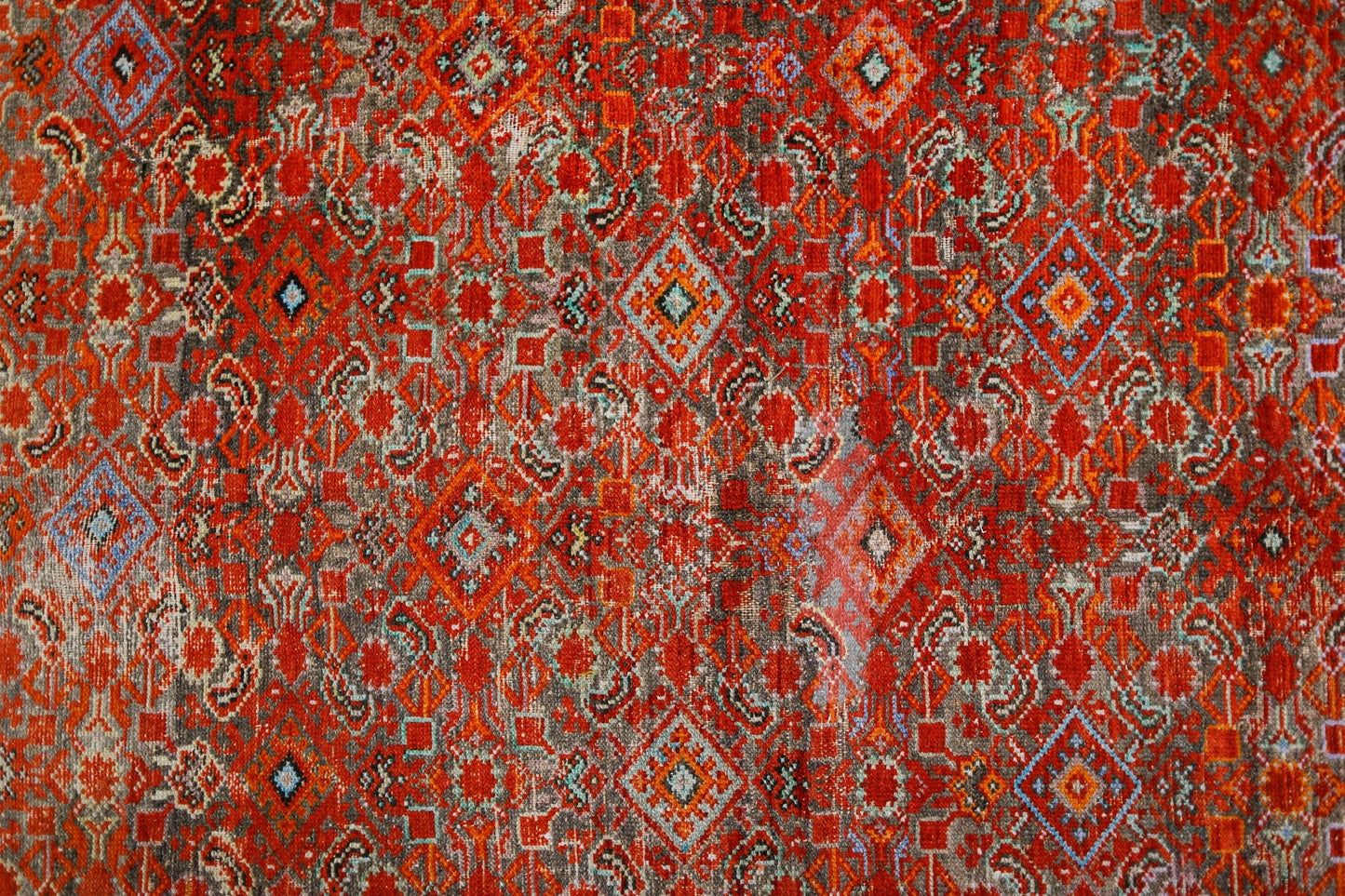 A vintage handmade Persian rug featuring a vibrant red geometric pattern with intricate details.