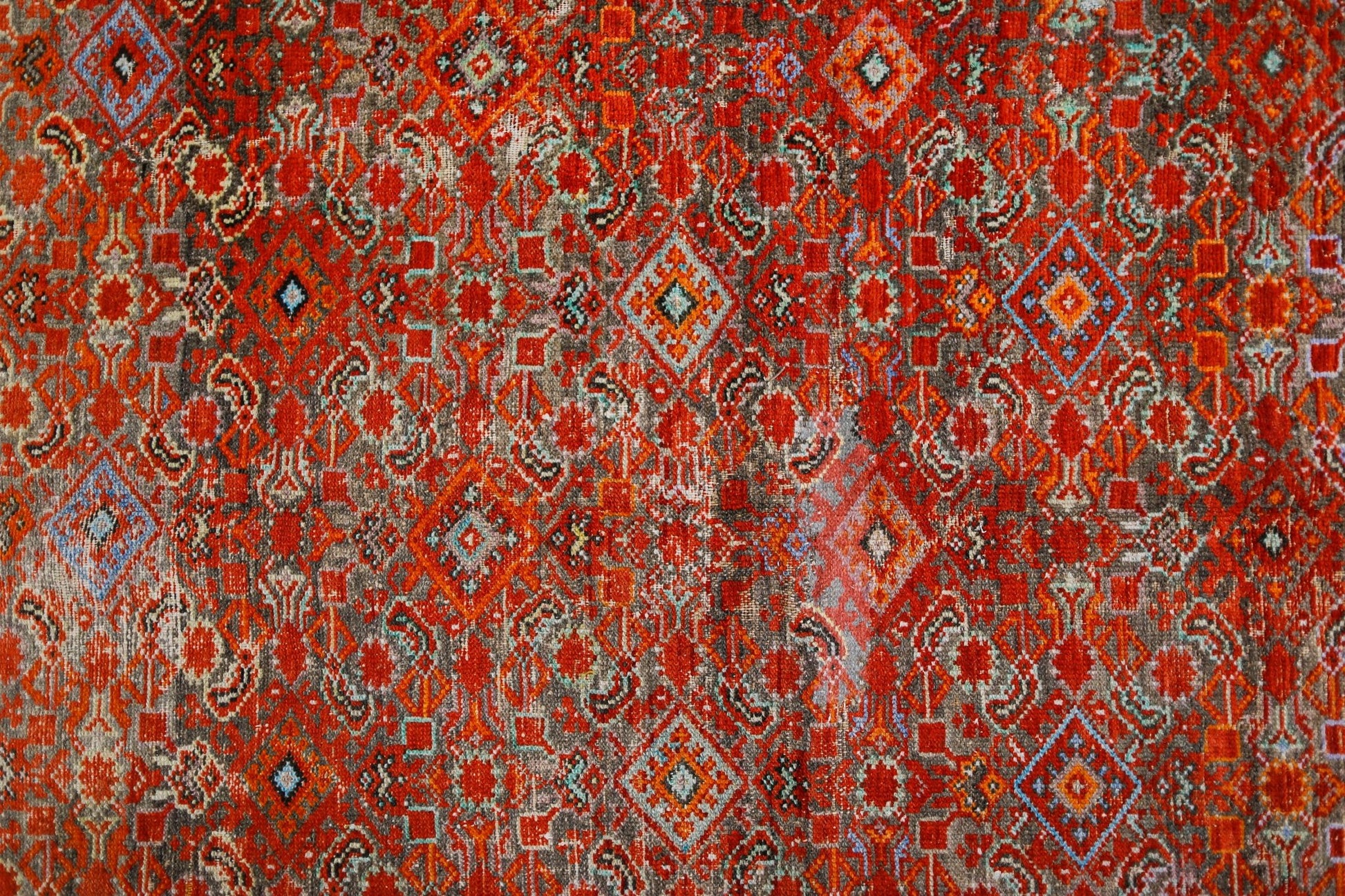 A vintage handmade Persian rug featuring a vibrant red geometric pattern with intricate details.