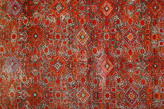 A vintage handmade Persian rug featuring a vibrant red geometric pattern with intricate details.
