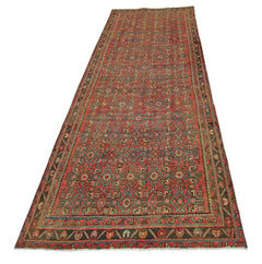A vintage handmade Persian runner rug featuring a geometric pattern in red, blue, and green tones.