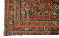 A vintage handmade Persian rug featuring intricate geometric patterns in red, green, and brown.