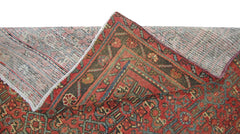 A vintage handmade Persian rug with a red and blue geometric pattern, shown folded to reveal backing.