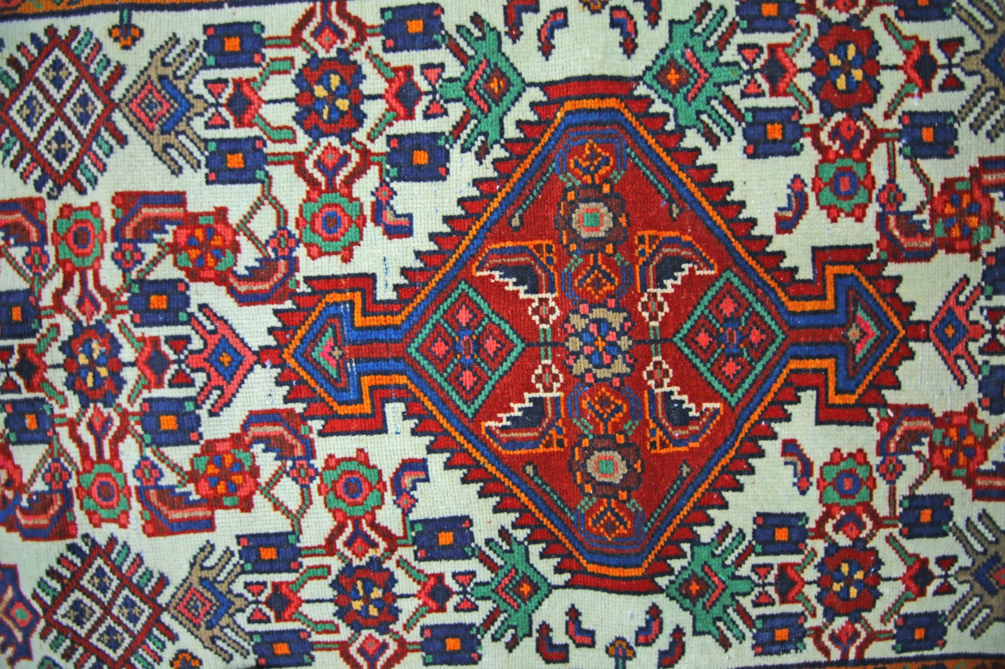 A vintage Persian Hamadan runner featuring a central red diamond medallion on a cream background.