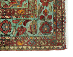 A corner detail of a vintage Persian Hossainabad runner featuring intricate floral patterns in red, blue, and green wool.