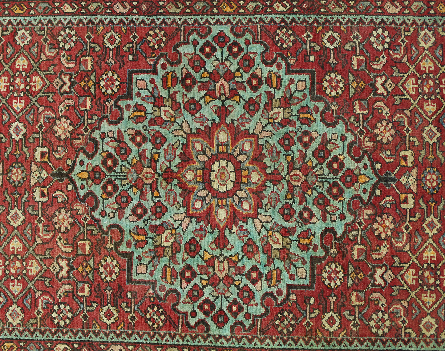 Vintage Persian Hossainabad runner featuring a central floral medallion on a red wool field.