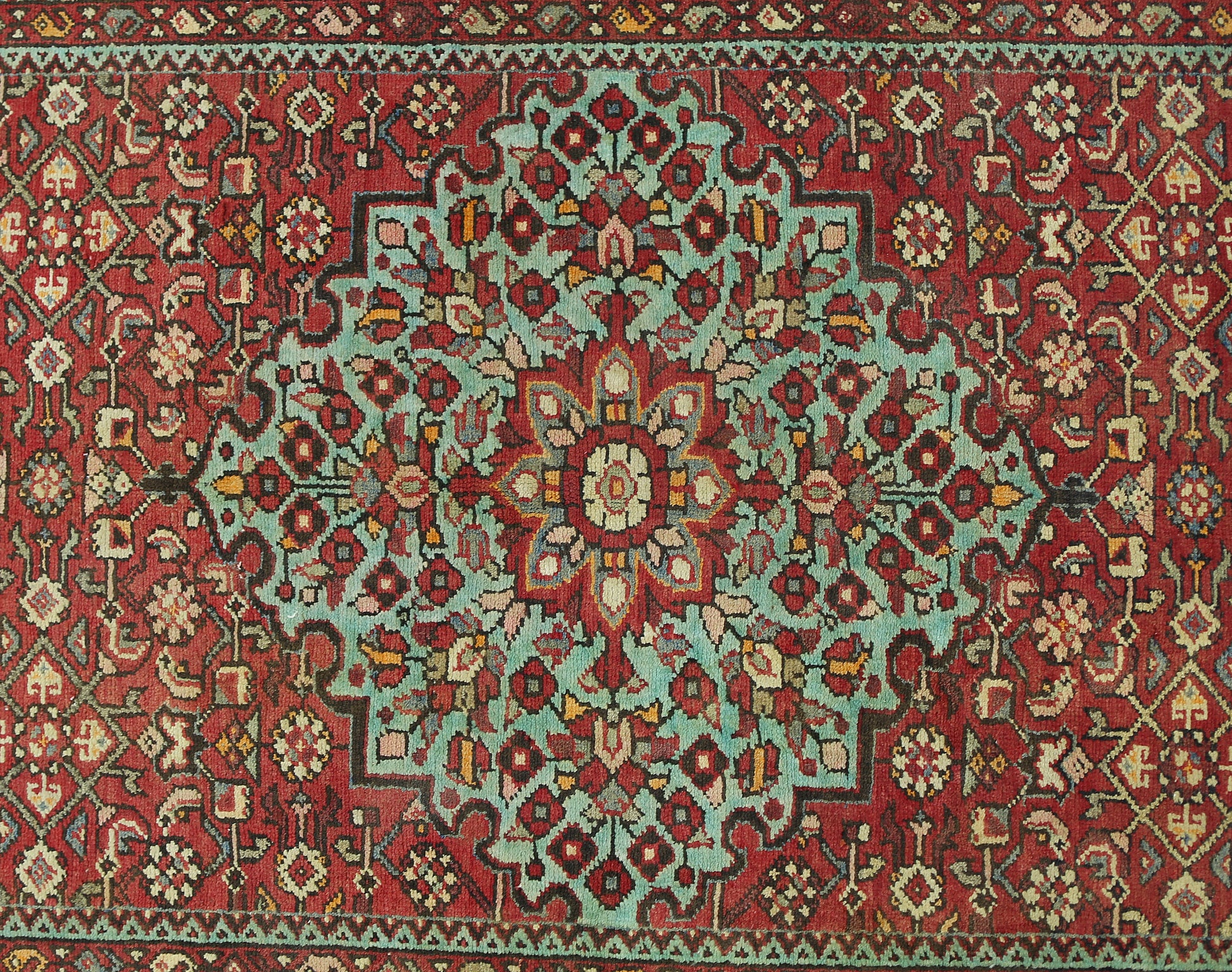 Vintage Persian Hossainabad runner featuring a central floral medallion on a red wool field.