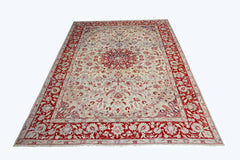 A vintage handmade Pakistani rug featuring a central floral medallion on a cream field with a red border.