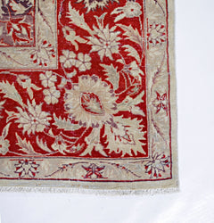 A vintage Pakistani rug featuring a red field with intricate floral patterns and a beige border.
