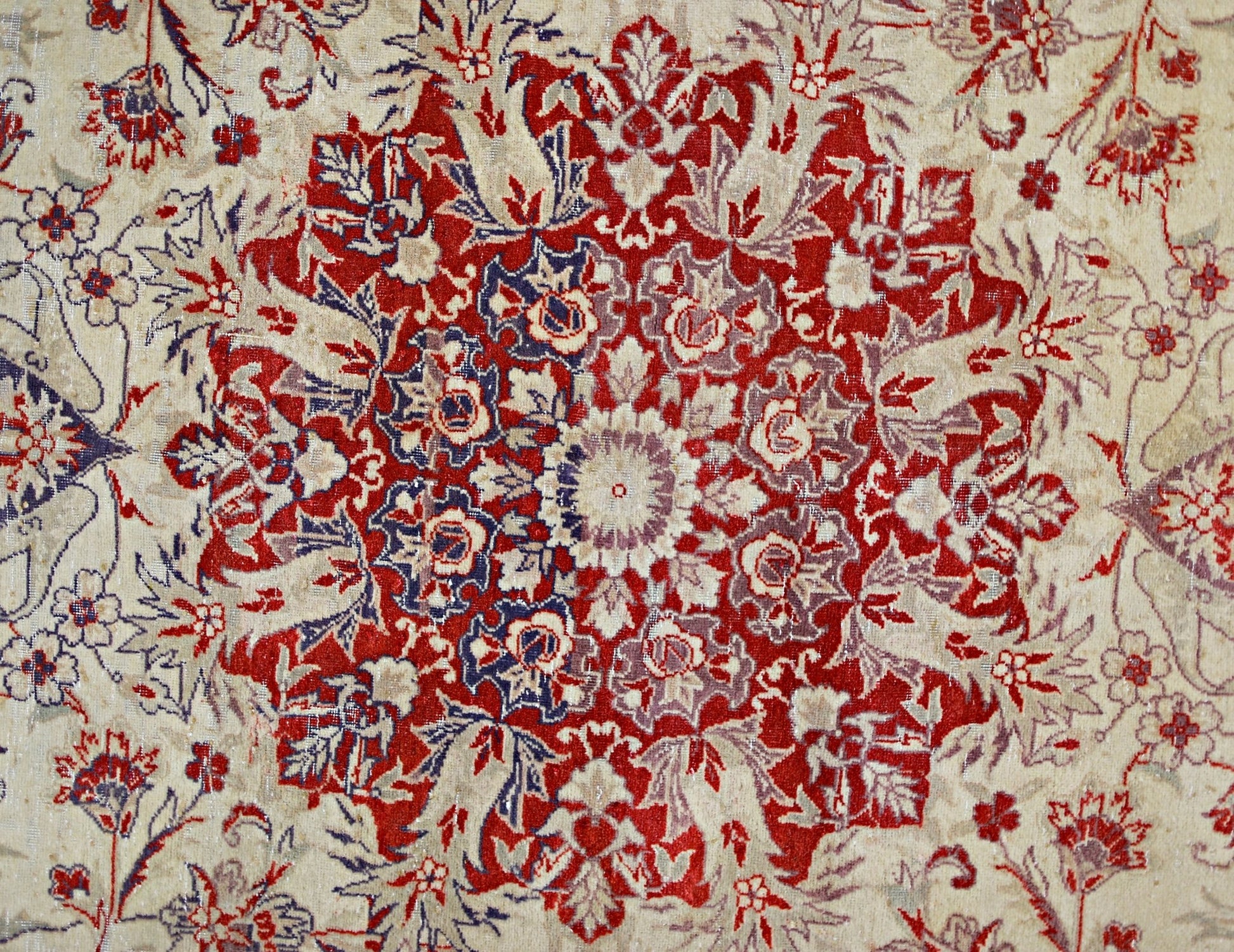 A vintage Pakistani rug featuring a detailed red and blue floral medallion on a cream background.