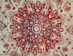 A vintage Pakistani rug featuring a detailed red and blue floral medallion on a cream background.