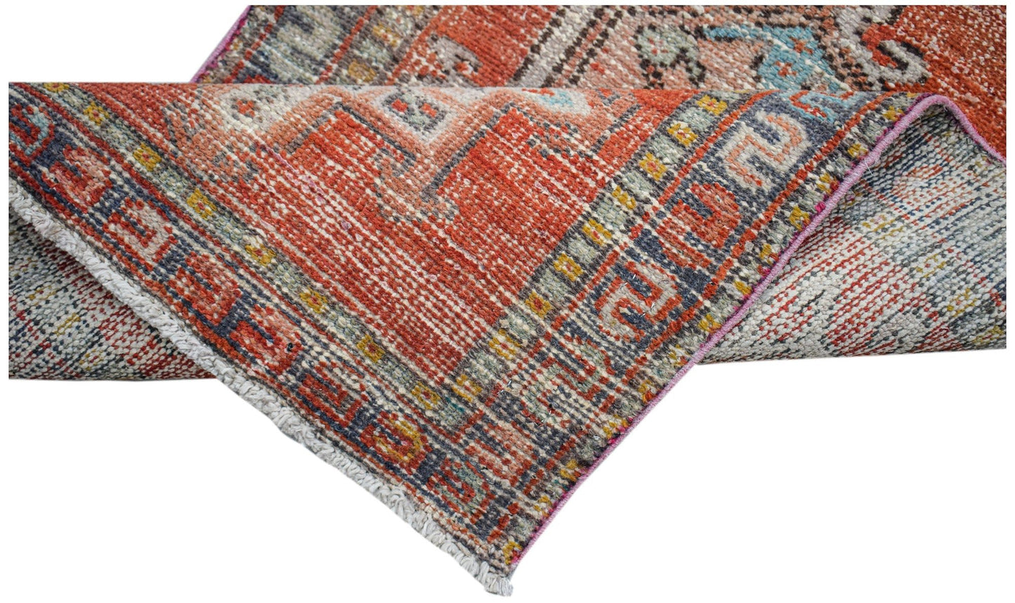 A vintage Persian Karaja runner featuring a geometric pattern in shades of red, blue, and cream.