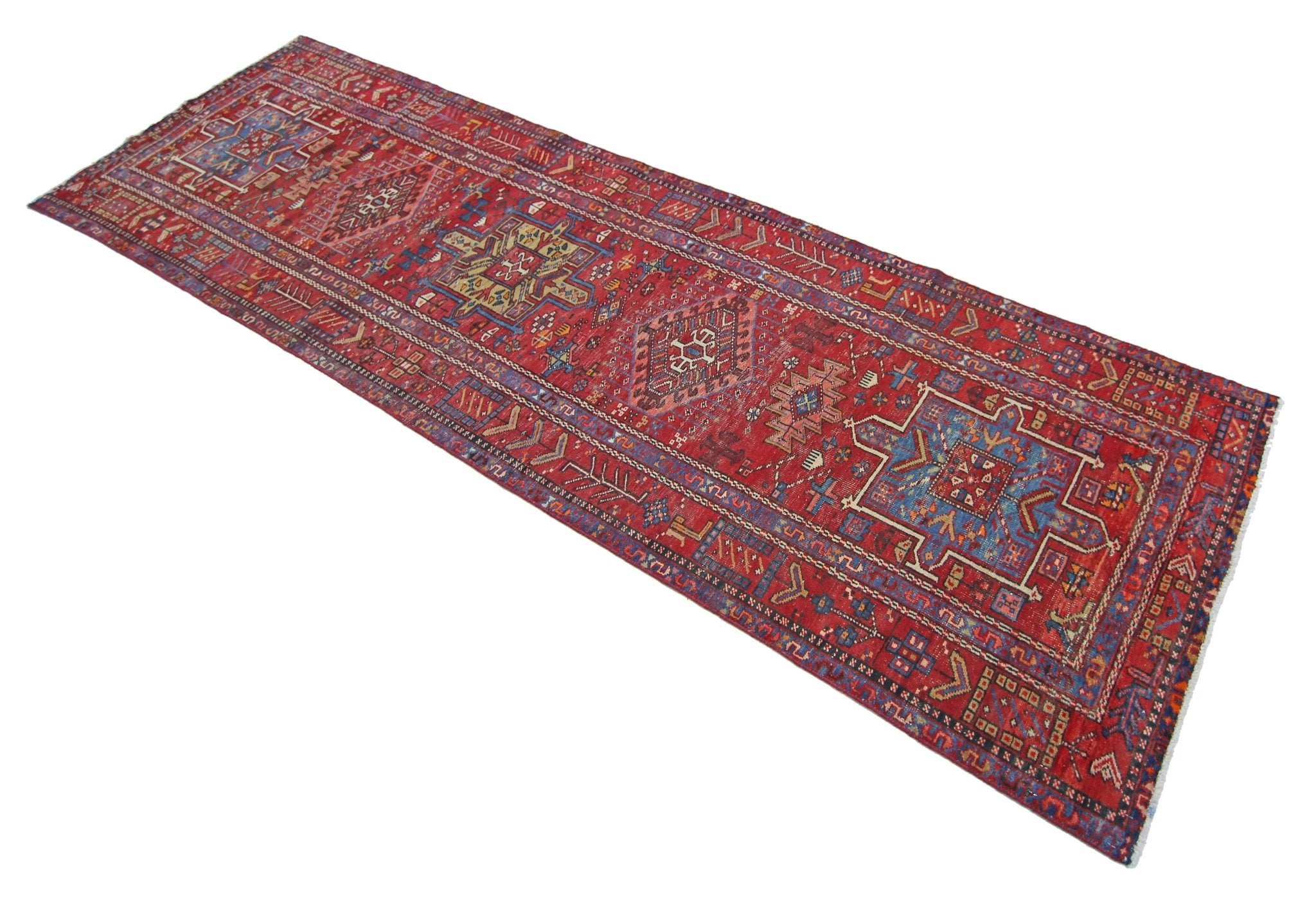 A vintage Persian Karaja runner rug featuring geometric patterns in red, blue, and cream tones.