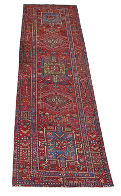 A vintage Persian Karaja runner rug featuring geometric medallions on a vibrant red field.