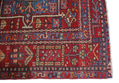 A vintage Persian Karaja runner featuring geometric patterns in red, blue, and cream wool.