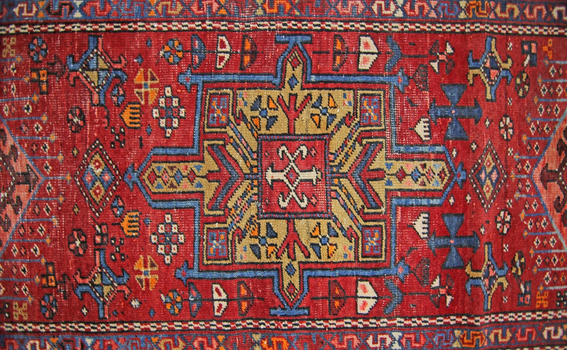 A vintage Persian Karaja runner featuring a geometric medallion pattern in red, blue, and gold.
