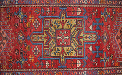 A vintage Persian Karaja runner featuring a geometric medallion pattern in red, blue, and gold.
