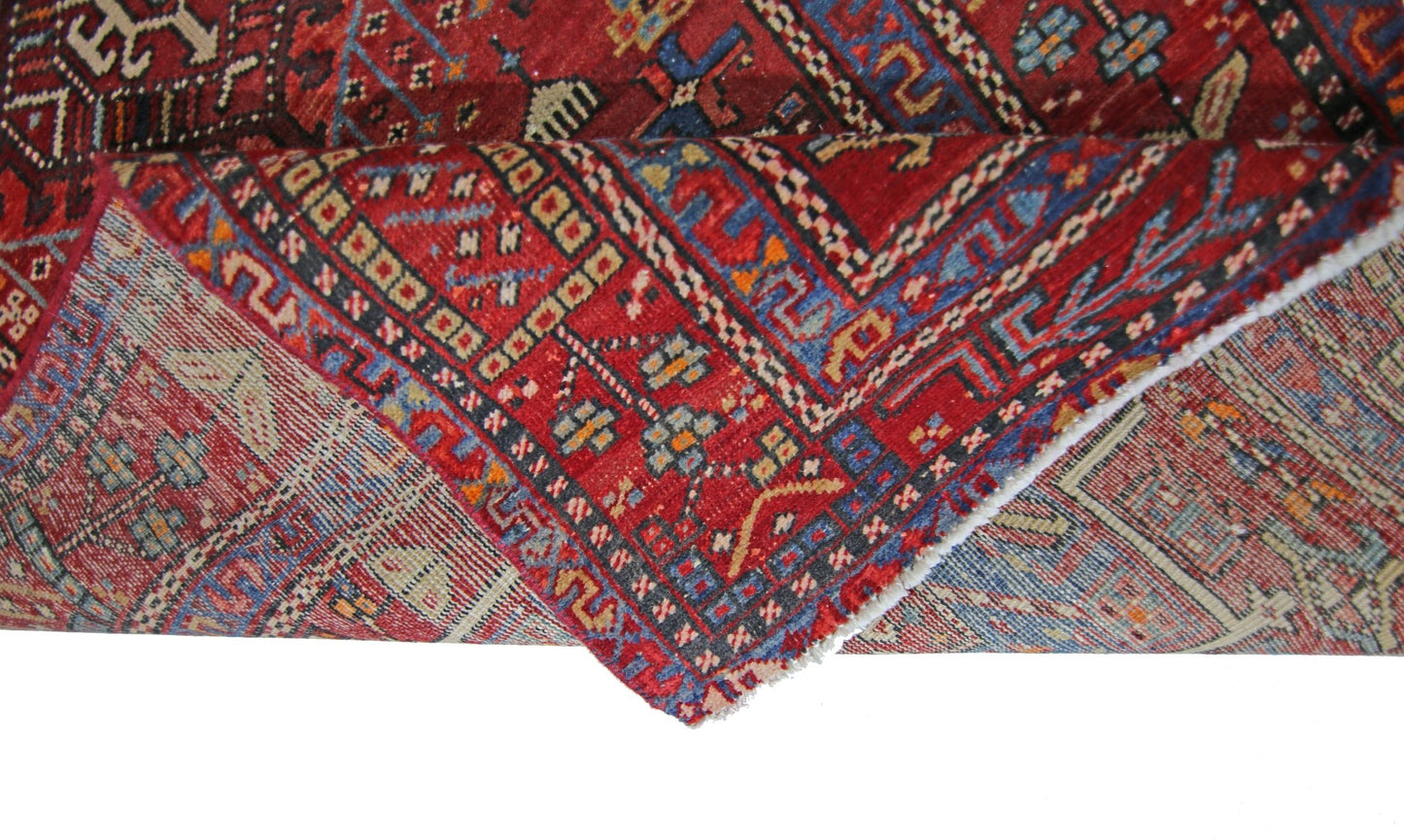 A vintage Persian Karaja runner featuring a geometric pattern in red, blue, and cream wool.