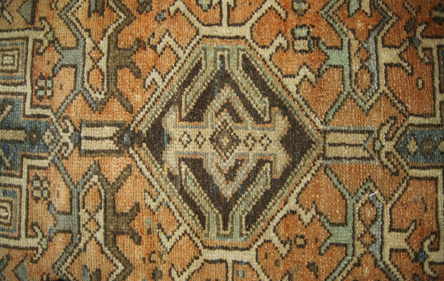 A vintage Persian Karaja runner featuring a geometric diamond pattern in orange, brown, and blue.