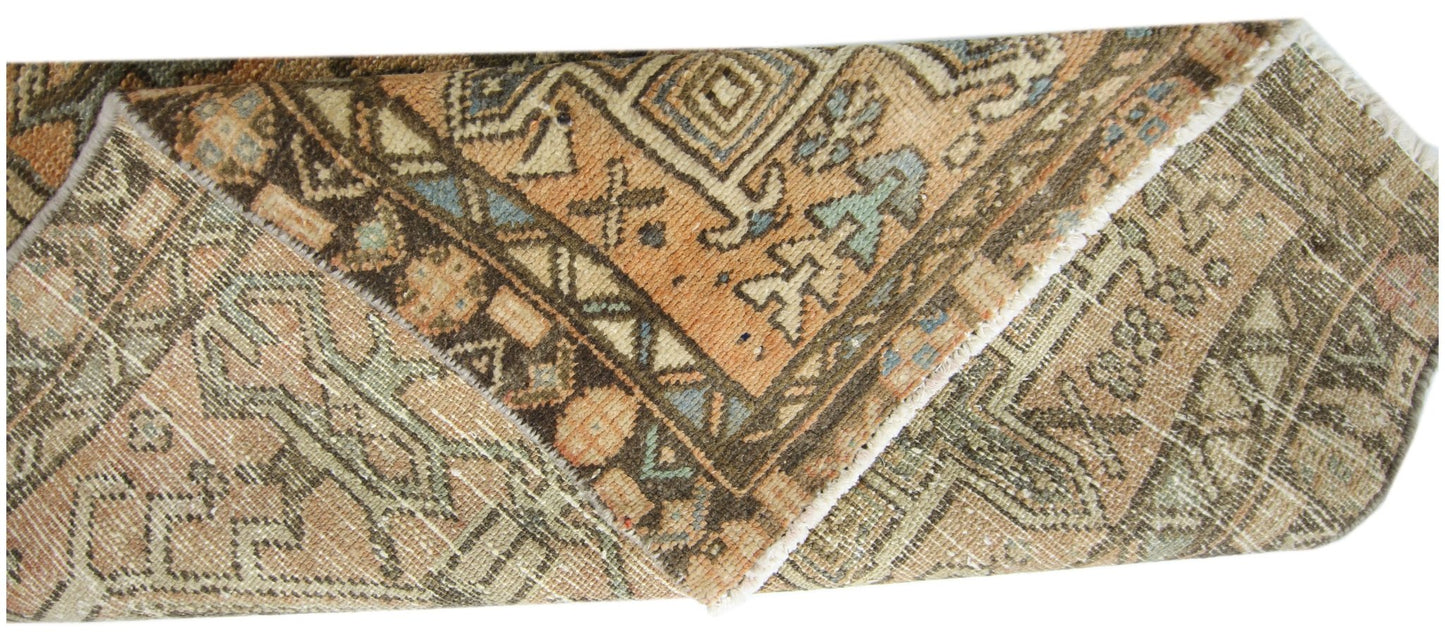 A folded vintage Persian Karaja runner featuring intricate geometric patterns in earthy tones.