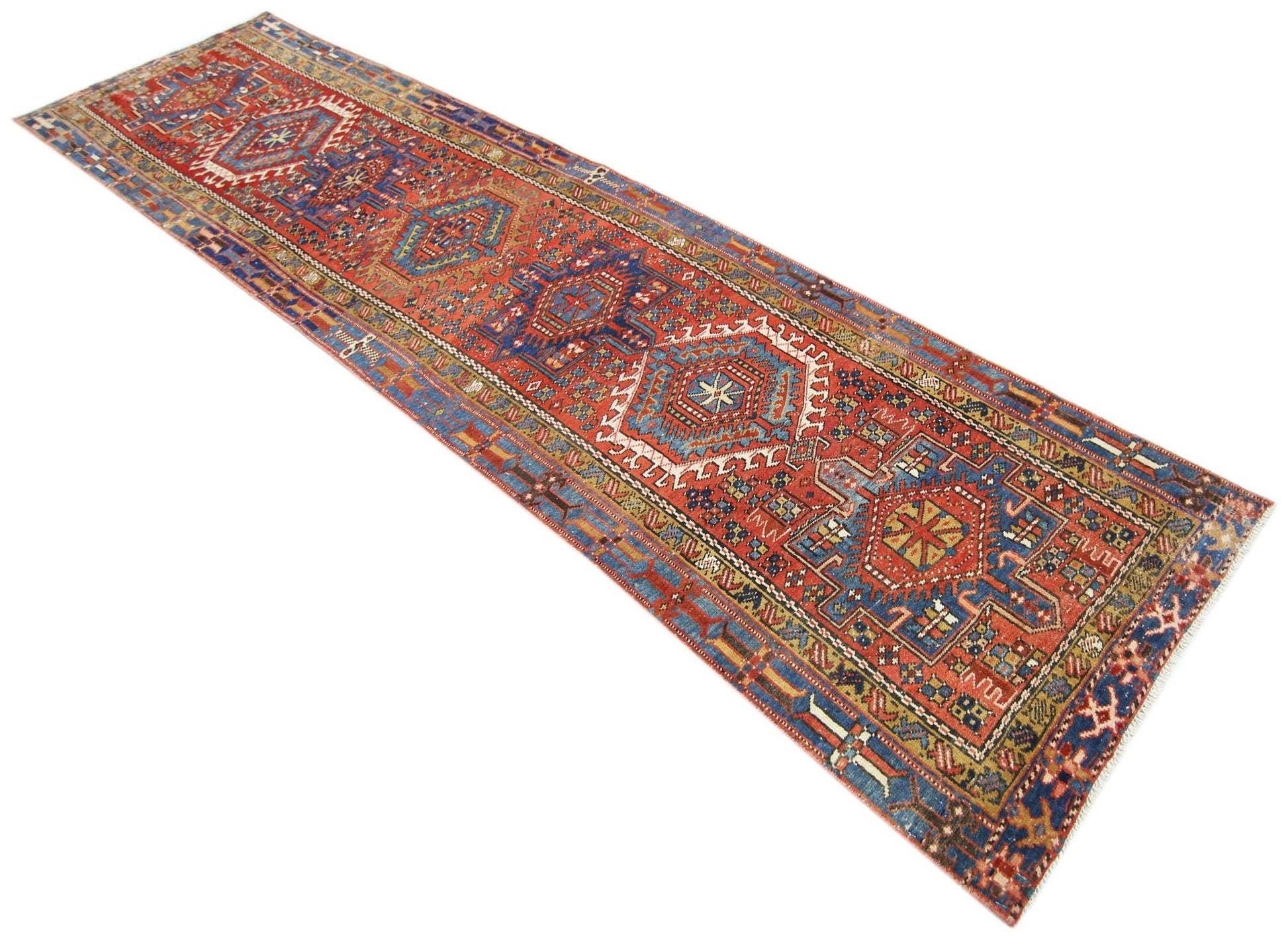 A vintage Persian Karaja runner rug featuring geometric medallions in red, blue, and cream tones.