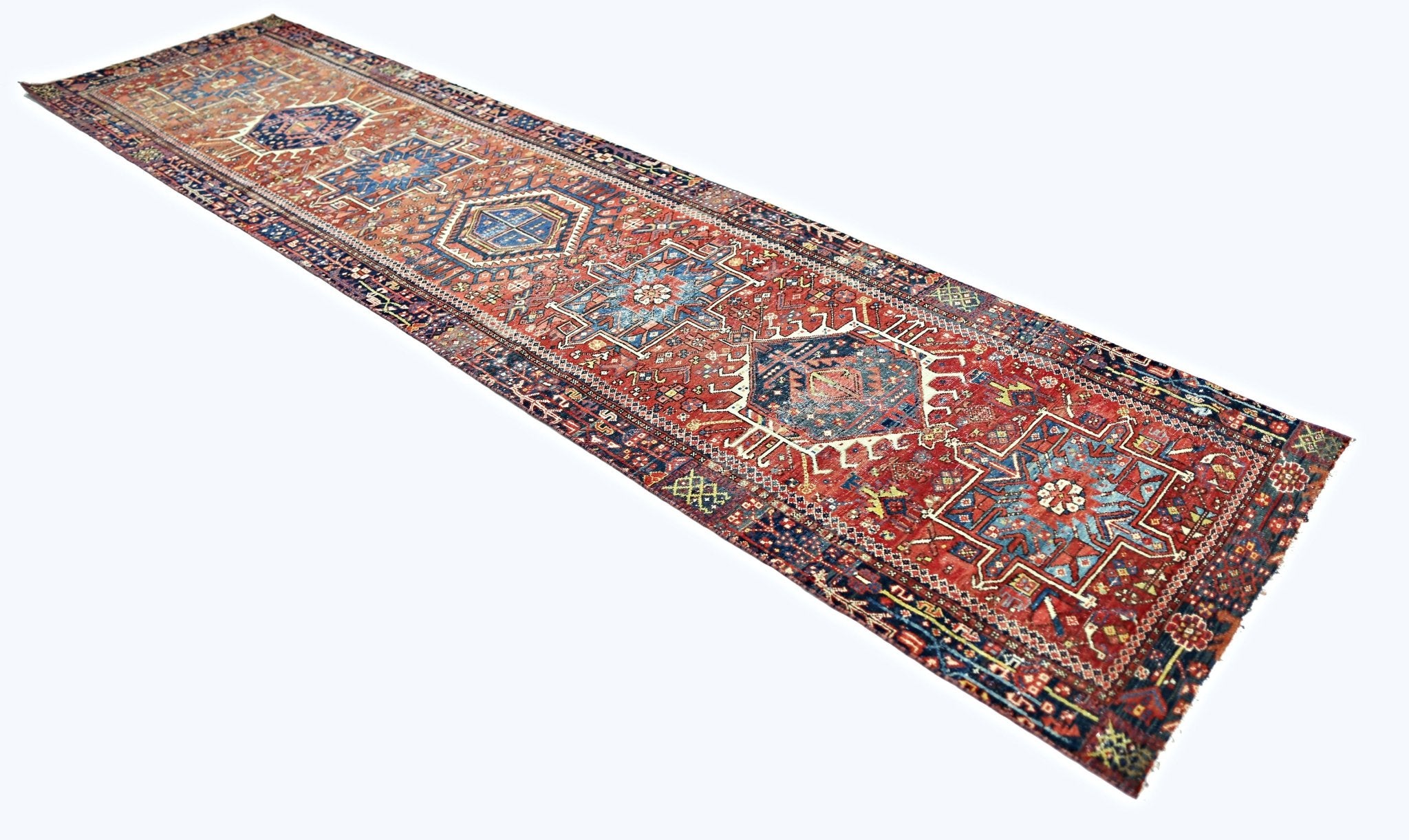 A vintage Persian Karaja runner rug featuring geometric medallions in red, blue, and cream tones.