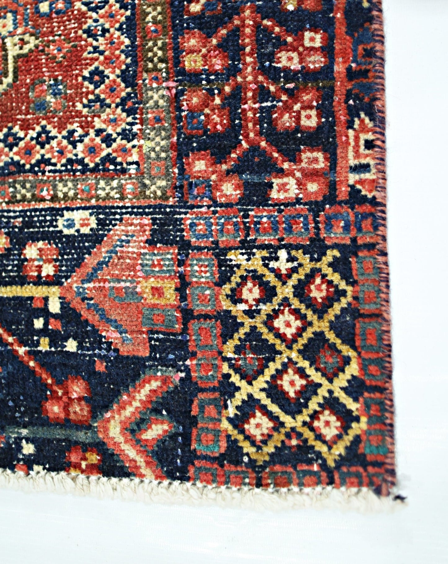 A vintage Persian Karaja runner featuring intricate geometric patterns in red, blue, and gold wool.
