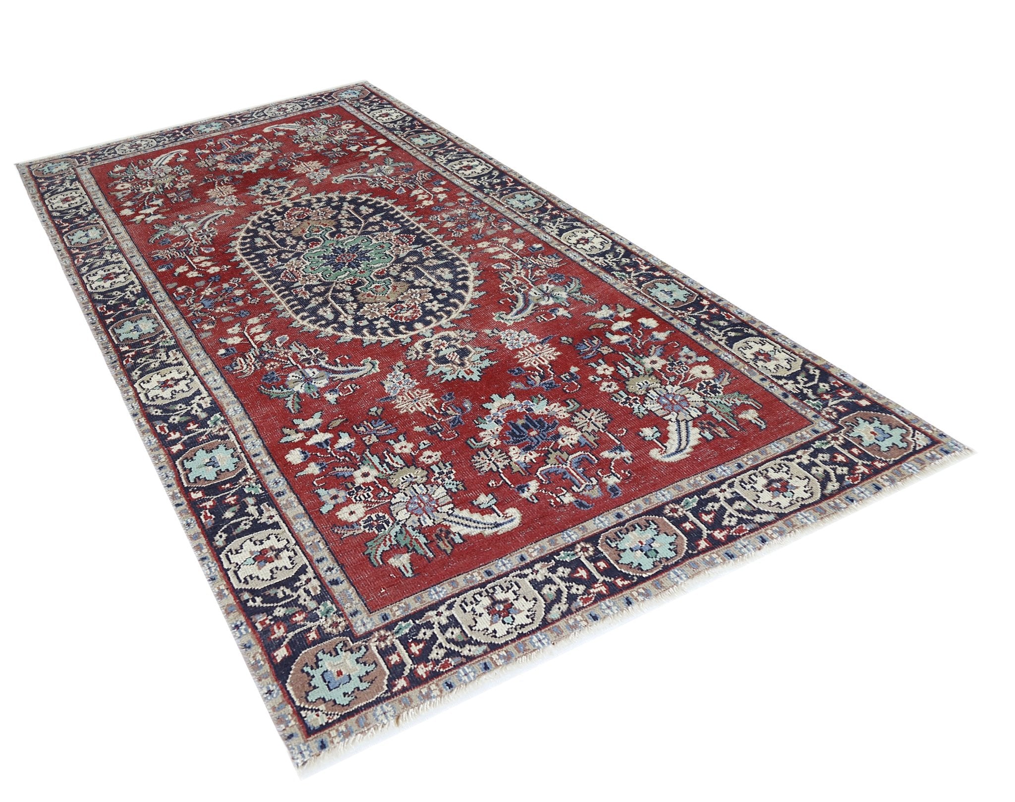 A vintage Persian Kashan rug featuring a central medallion and floral patterns on a red background.