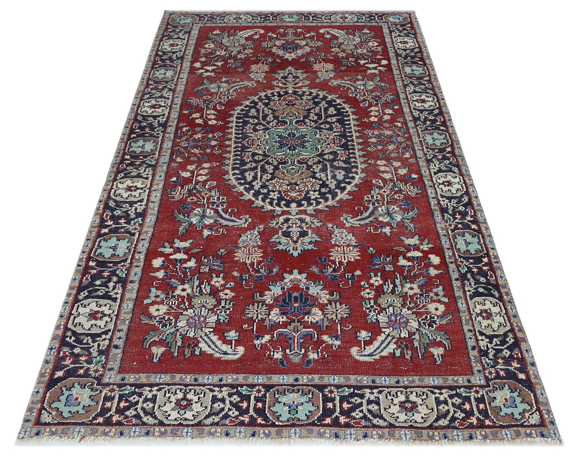 A vintage Persian Kashan rug featuring a central medallion and floral patterns on a red background.