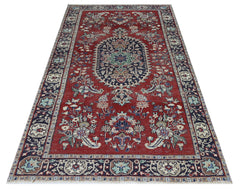 A vintage Persian Kashan rug featuring a central medallion and floral patterns on a red background.