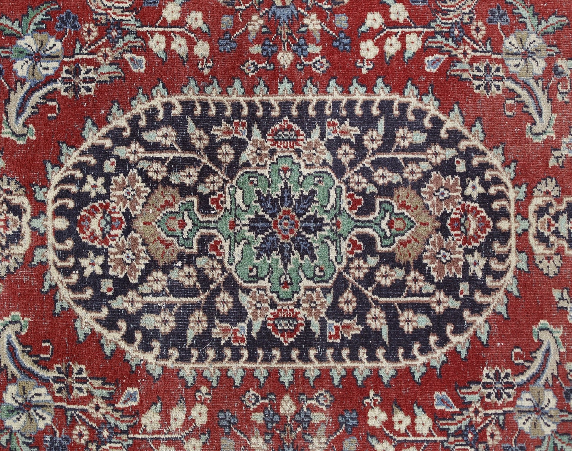 A vintage Persian Kashan rug featuring a central floral medallion on a dark blue and red field.