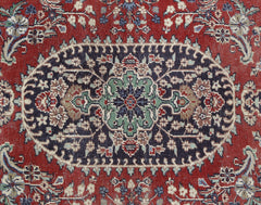 A vintage Persian Kashan rug featuring a central floral medallion on a dark blue and red field.