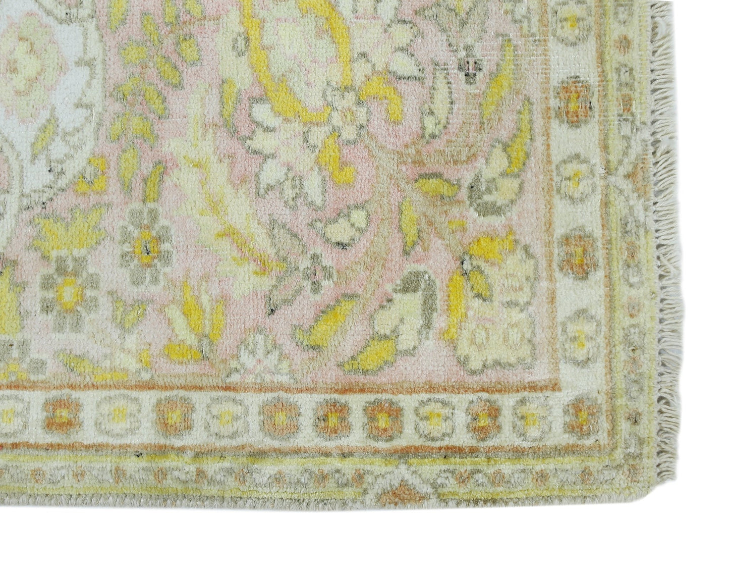 A vintage Persian Kashan rug featuring a floral pattern in soft pink, yellow, and cream tones.