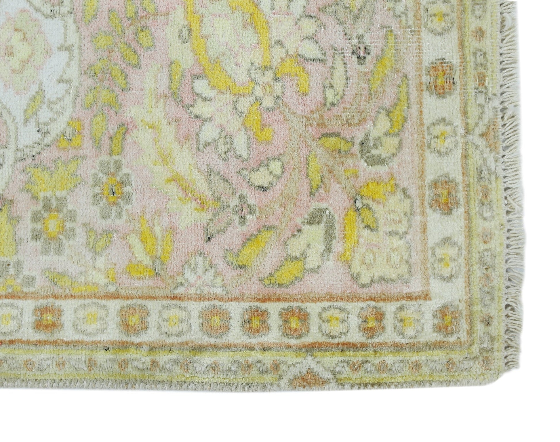 A vintage Persian Kashan rug featuring a floral pattern in soft pink, yellow, and cream tones.