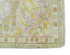 A vintage Persian Kashan rug featuring a floral pattern in soft pink, yellow, and cream tones.