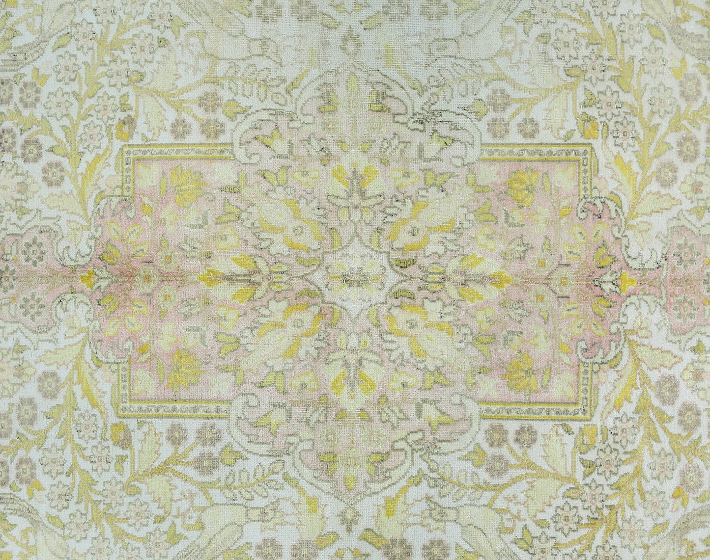 A vintage Persian Kashan rug featuring a floral pattern in soft pink, yellow, and cream tones.