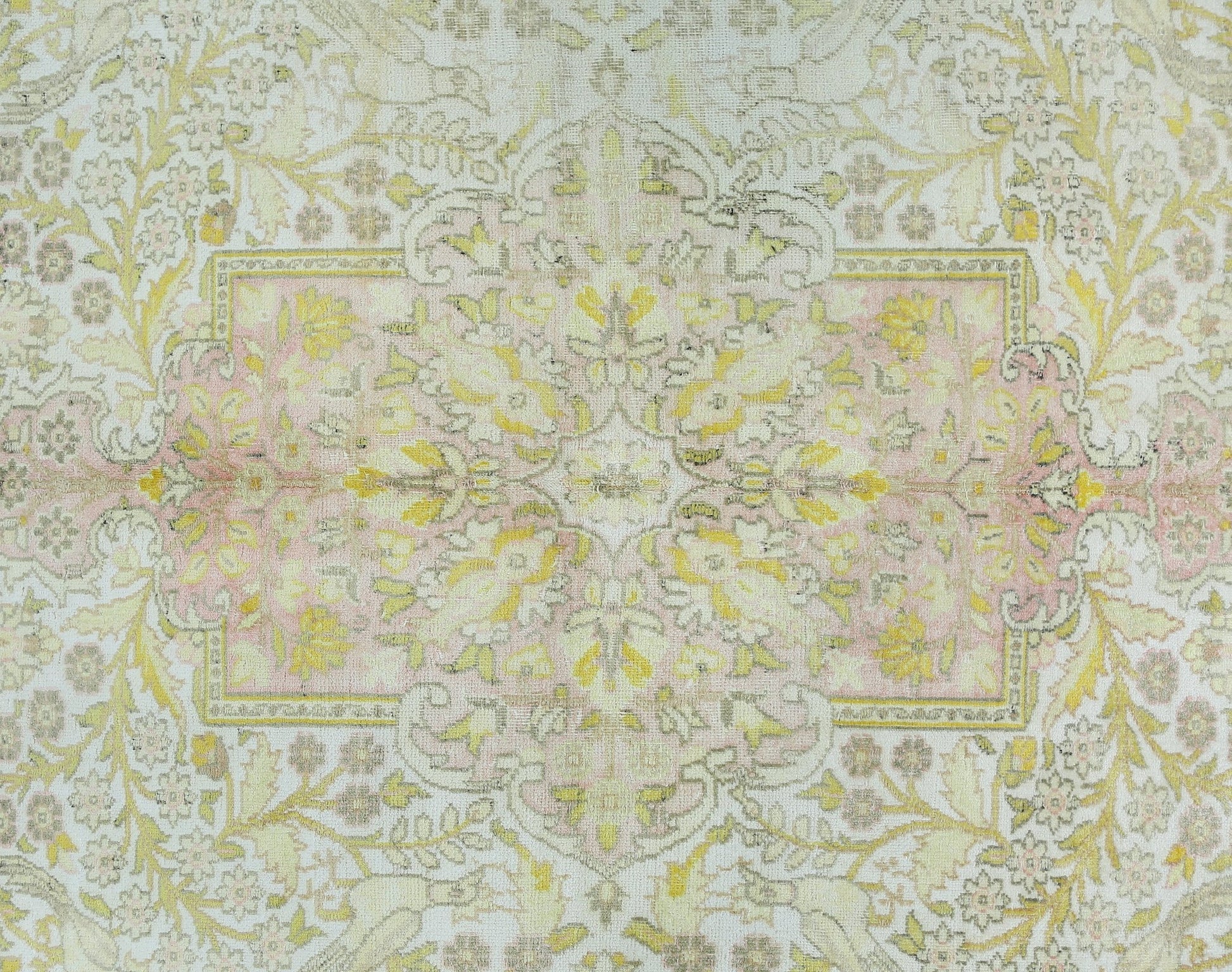 A vintage Persian Kashan rug featuring a floral pattern in soft pink, yellow, and cream tones.