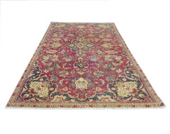 A vintage Persian Kashan rug featuring a traditional floral pattern in red, blue, and cream tones.