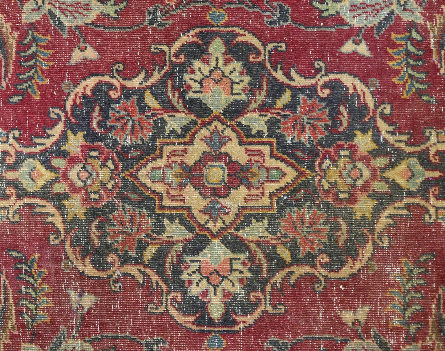 A vintage Persian Kashan rug featuring a detailed floral medallion pattern in red and dark tones.