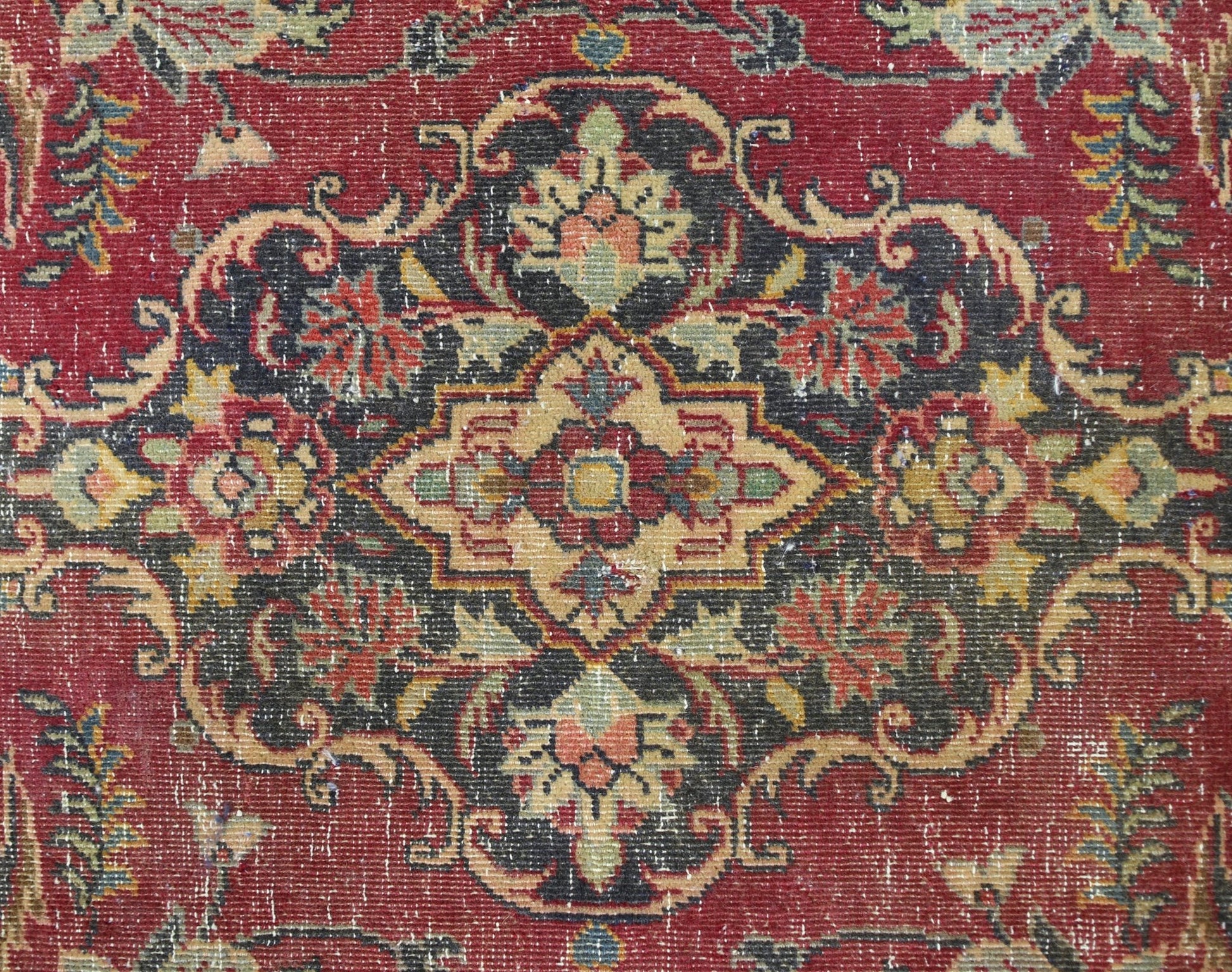 A vintage Persian Kashan rug featuring a detailed floral medallion pattern in red and dark tones.