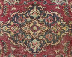 A vintage Persian Kashan rug featuring a detailed floral medallion pattern in red and dark tones.
