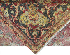 A folded vintage Persian Kashan rug featuring intricate floral patterns in red, black, and gold.