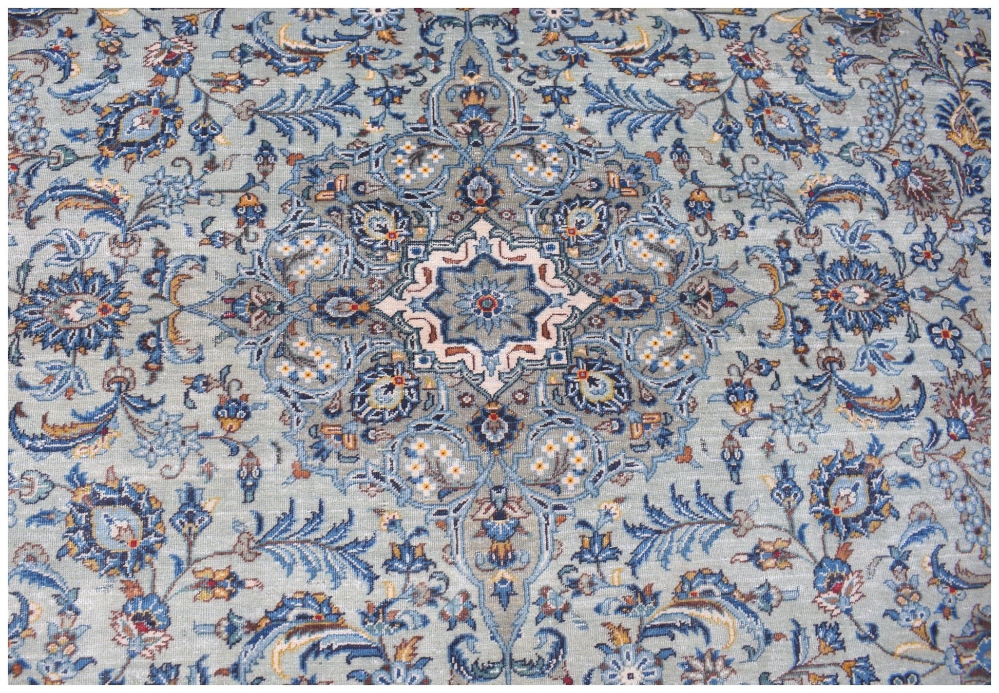 A vintage Persian Kashan rug featuring intricate floral patterns in shades of blue and cream.