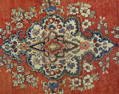 A vintage Persian Tabriz rug featuring a central floral medallion on a red field.