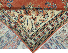 A vintage Persian Tabriz rug with a floral pattern, shown folded to reveal its woven underside.