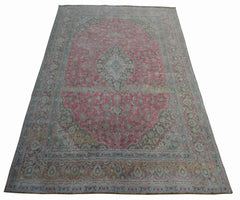 A vintage handwoven Persian Kashan rug featuring a central floral medallion in pink and grey tones.