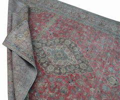 A vintage Persian Kashan rug featuring a faded floral pattern in pink, grey, and blue tones.